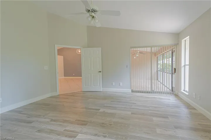 Empty room with a ceiling fan, light wood finished floors, baseboards, and high vaulted ceiling