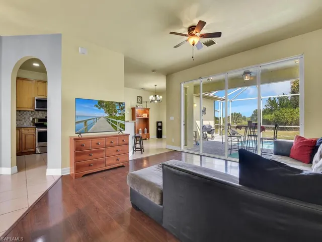 Living area with ceiling fan, arched walkways, visible vents, wood finished floors, and baseboards