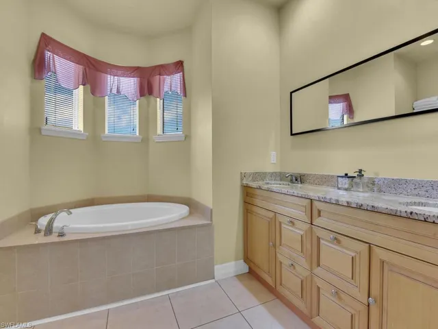 Bathroom with a sink, tile patterned floors, double vanity, and a garden tub