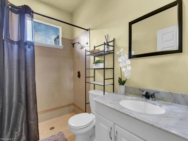 Full bathroom featuring vanity, a tile shower, and toilet