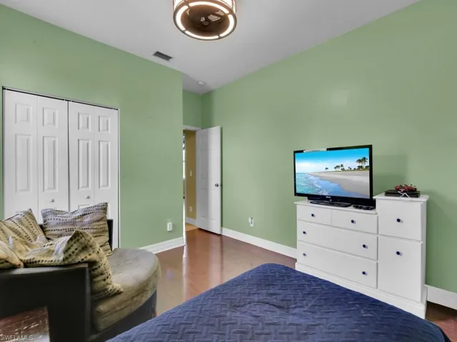 Bedroom featuring wood finished floors, baseboards, a closet, and visible vents