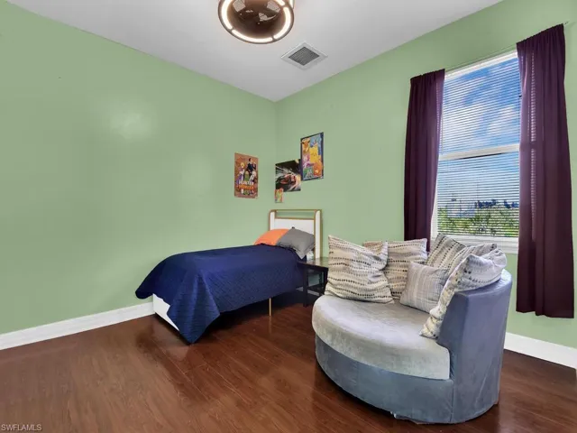 Bedroom with wood finished floors, baseboards, and visible vents
