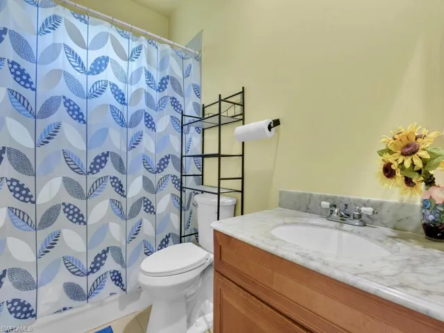 Full bathroom with a shower with shower curtain, vanity, toilet, and tile patterned flooring