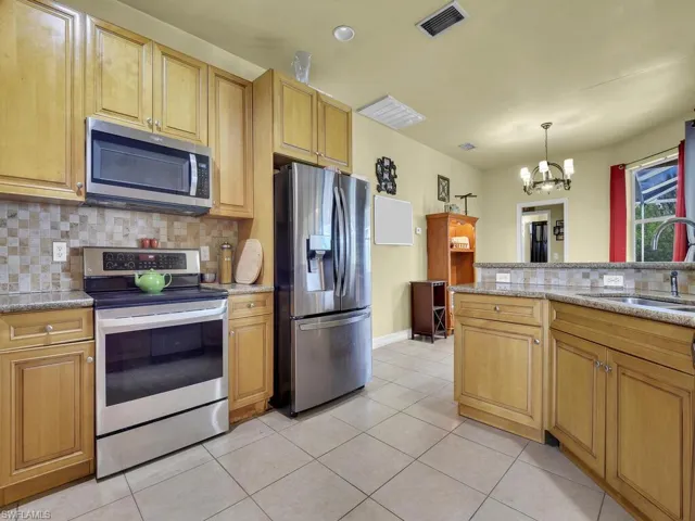 Kitchen with visible vents, appliances with stainless steel finishes, a sink, a notable chandelier, and backsplash