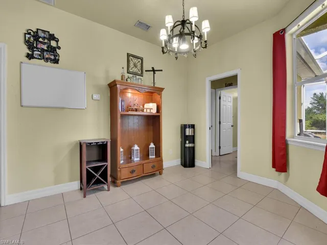 Dining room featuring light tile patterned floors, visible vents, baseboards, and an inviting chandelier