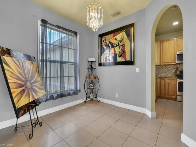 Dining room featuring arched walkways, light tile patterned floors, baseboards, and visible vents