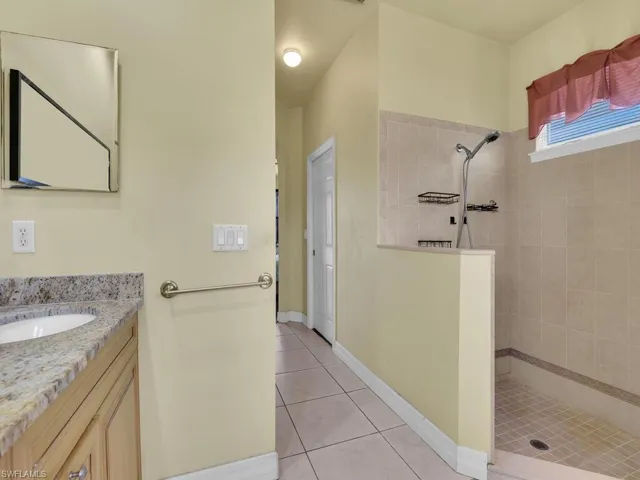 Bathroom with tile patterned floors, walk in shower, vanity, and baseboards