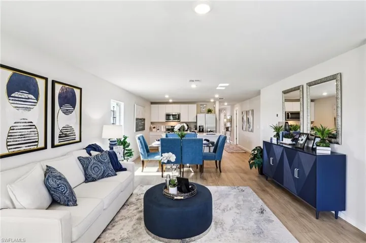 Model home. Living room featuring light wood-type flooring and recessed lighting