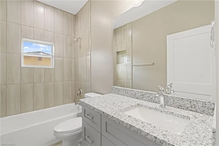Full bathroom featuring tiled shower / bath combo, toilet, and vanity