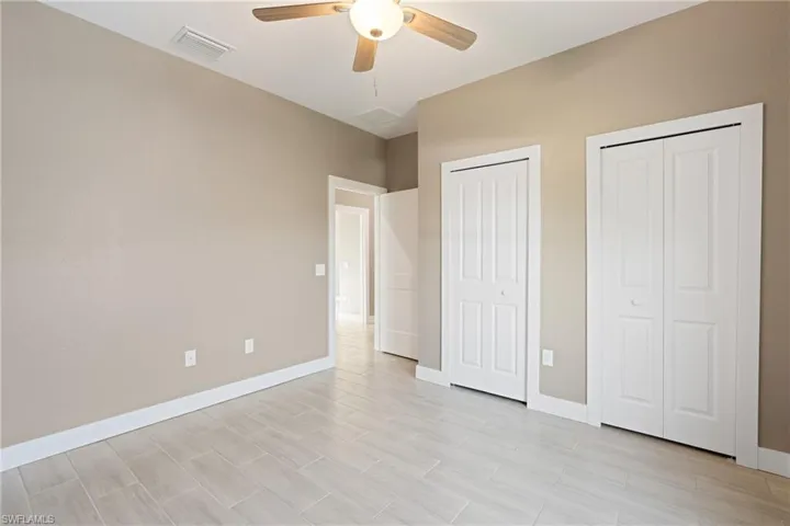 Unfurnished bedroom with multiple closets and ceiling fan