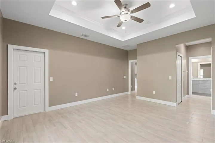 Unfurnished room with crown molding, ceiling fan, and a raised ceiling