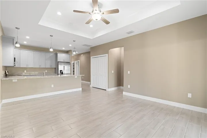 Unfurnished living room featuring ceiling fan and a raised ceiling
