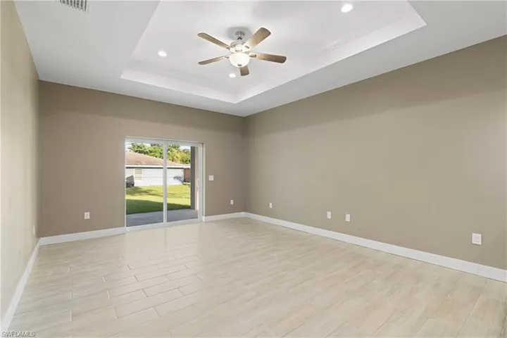 Empty room with ceiling fan and a raised ceiling