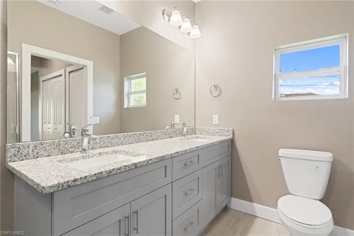 Bathroom featuring tile patterned floors, double sink vanity, and toilet