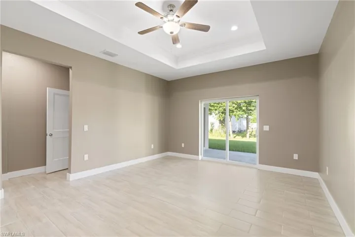 Unfurnished room with ceiling fan and a raised ceiling