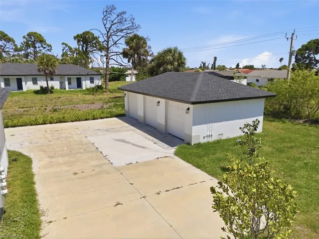 Detached3-car garage with white overhead doors and exterior lighting fixtures - 1 per unit