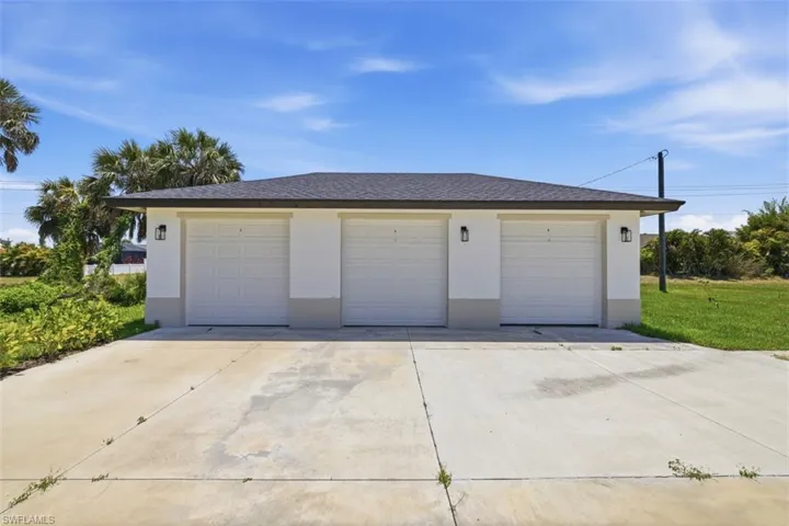 1 car garage per unit-Three-car garage featuring white paneled doors, stucco exterior, and a dark shingle roof