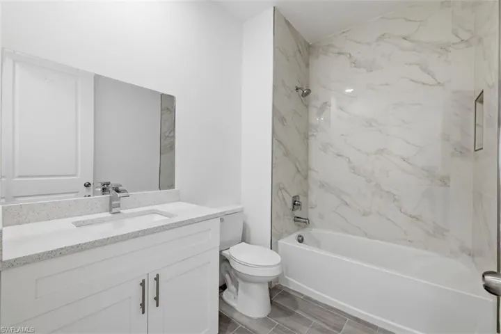 Guest Bathroom- Full bathroom featuring a white vanity with a quartz-finish countertop, undermount sink, and chrome faucet