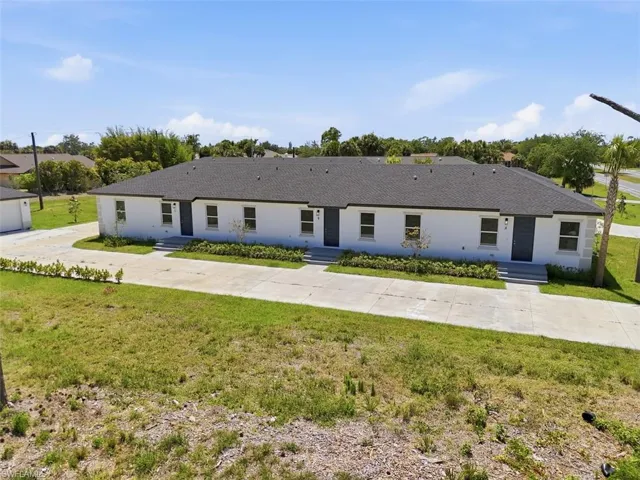 Contemporary multi-unit property featuring white stucco exterior and dark shingle roofing