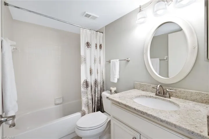 Coastal Inspired guest bathroom with granite countertops and tub/shower combo