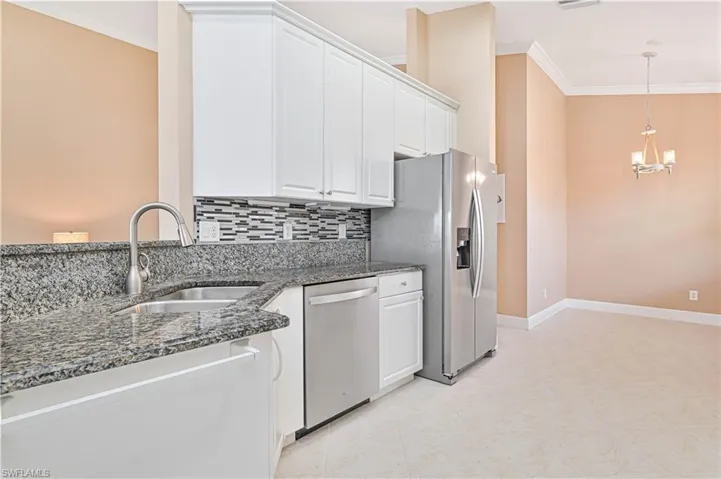 Kitchen featuring decorative backsplash, appliances with stainless steel finishes, dark stone counters, sink, and white cabinetry