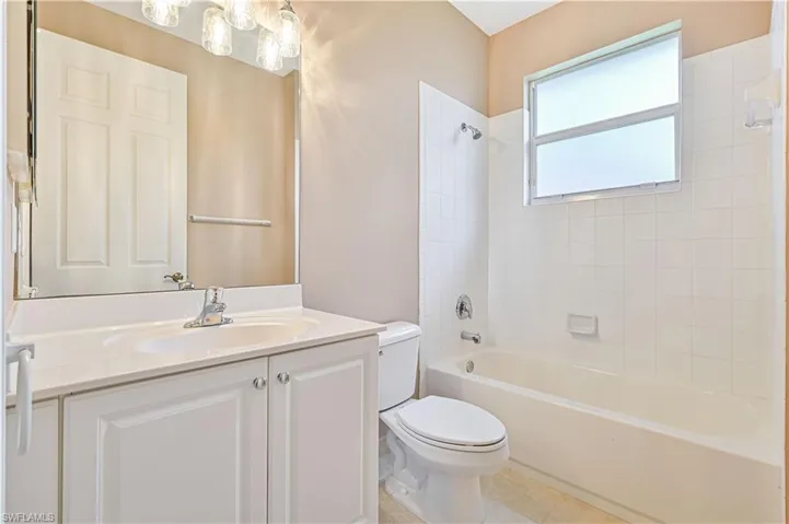 Full bathroom with tile patterned floors, vanity, toilet, and tiled shower / bath combo