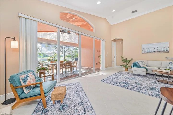 Living room with ceiling fan, high vaulted ceiling, light tile patterned flooring, and ornamental molding