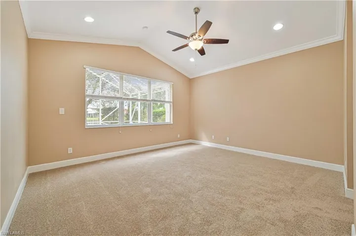 Carpeted empty room featuring crown molding, ceiling fan, and vaulted ceiling