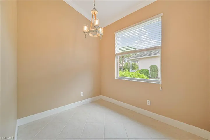 Spare room featuring ornamental molding, light tile patterned floors, and a chandelier