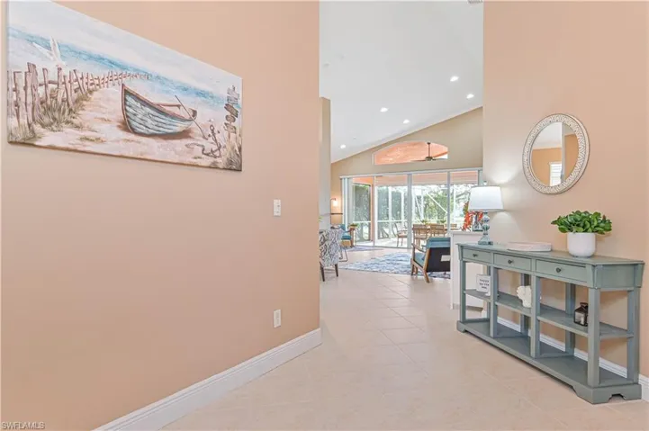 Hallway with light tile patterned floors and high vaulted ceiling