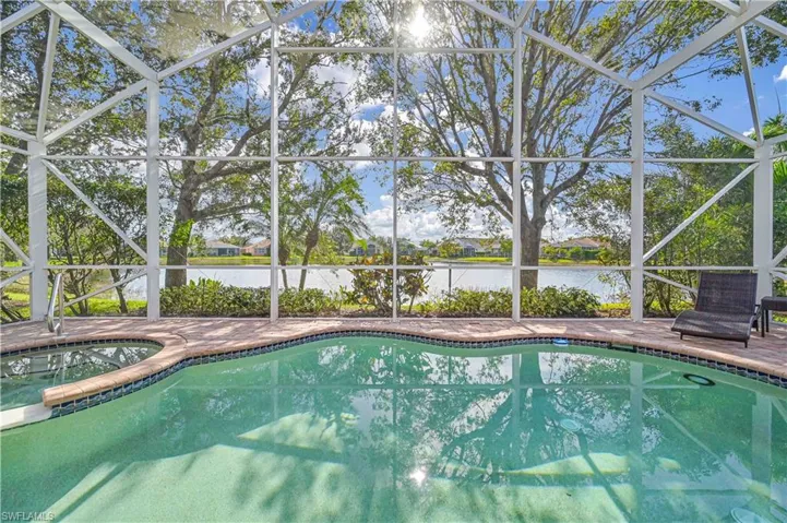 View of swimming pool with glass enclosure, a water view, an in ground hot tub, and a patio