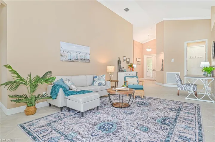 Tiled living room with high vaulted ceiling and crown molding