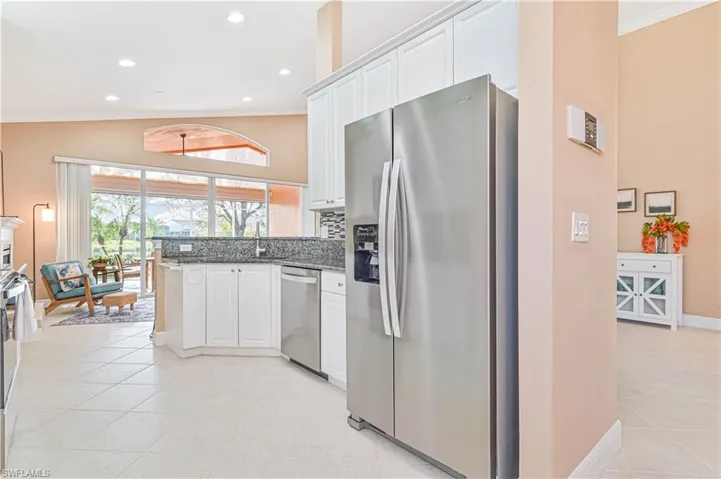 Kitchen with stainless steel appliances, light tile patterned floors, dark stone counters, white cabinets, and ornamental molding
