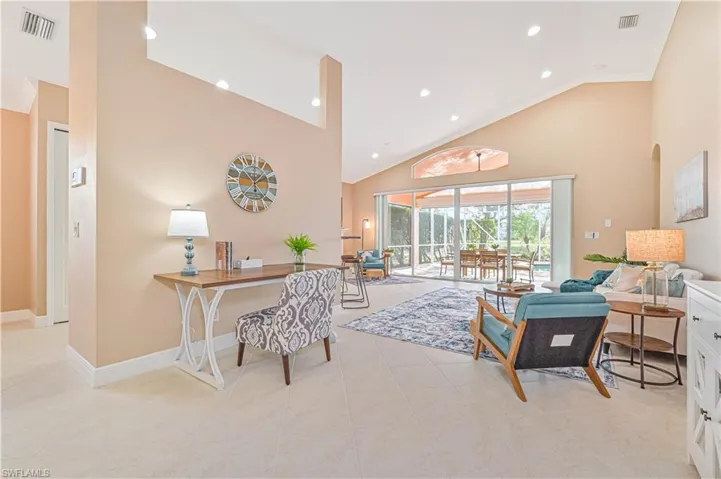 Living room with light tile patterned flooring, ornamental molding, and high vaulted ceiling