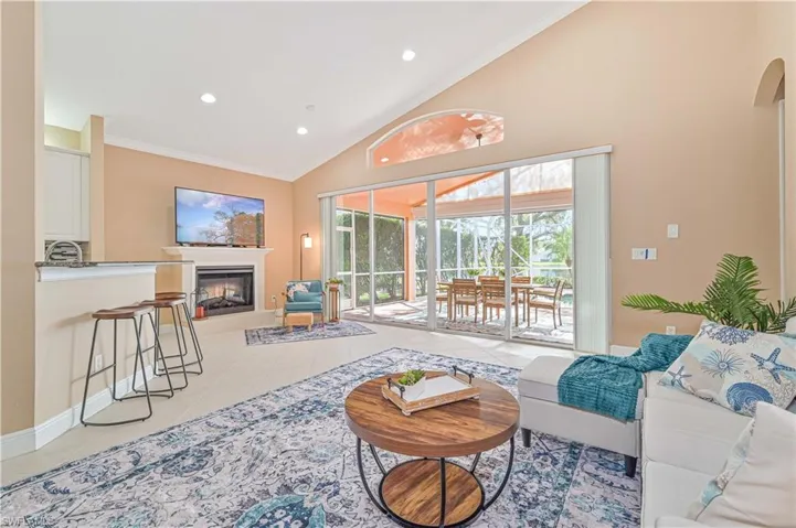 Living room with tile patterned flooring, high vaulted ceiling, and ornamental molding