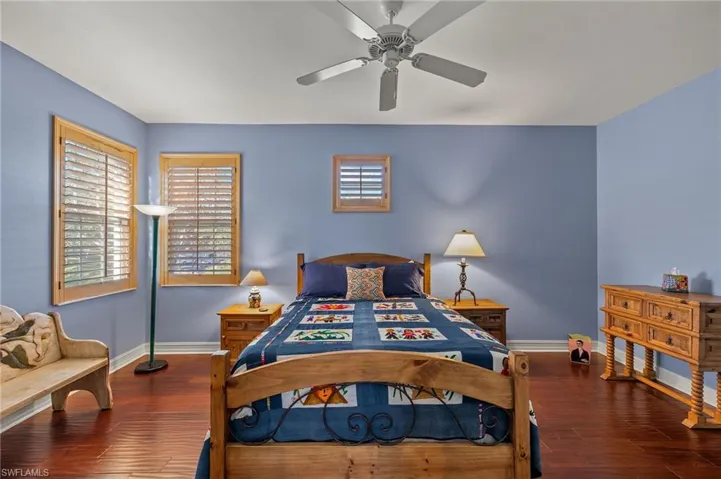 Guest bedroom with hardwood floors, walk in closet and plantation shutters.