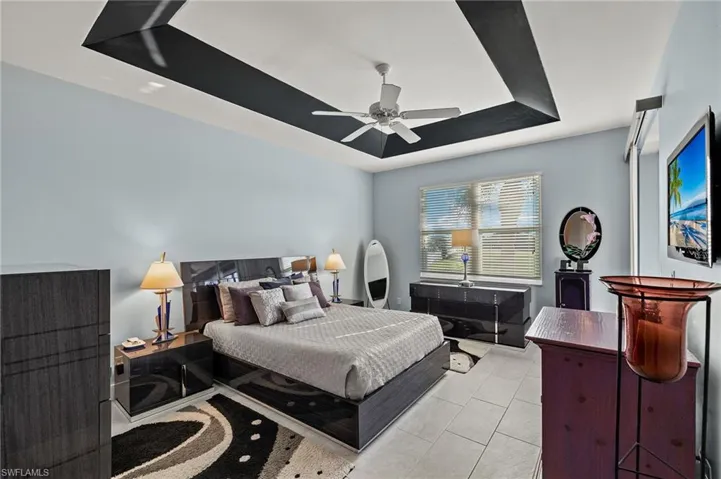 Spacious primary bedroom with ceramic tile and tray ceiling.