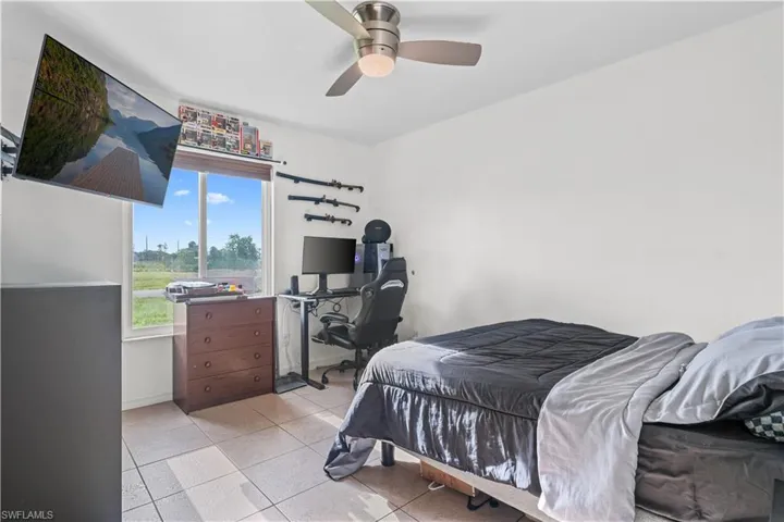 Tiled bedroom with a desk and ceiling fan