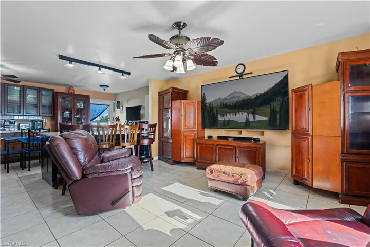 Living area featuring ceiling fan, light tile patterned floors, and rail lighting