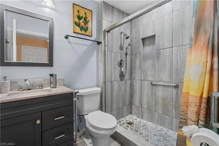 Bathroom featuring vanity, a stall shower, and a textured wall