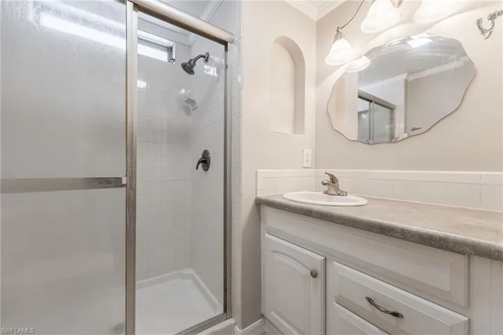 Full bath featuring crown molding, vanity, and a stall shower