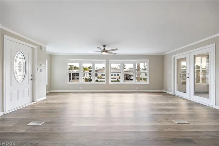 Foyer with ornamental molding, wood finished floors, a ceiling fan, and french doors