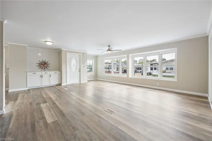 Unfurnished living room with crown molding, ceiling fan, and light wood finished floors
