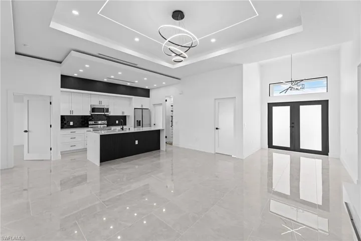 Kitchen with an inviting chandelier, pendant lighting, stainless steel appliances, and an island with sink