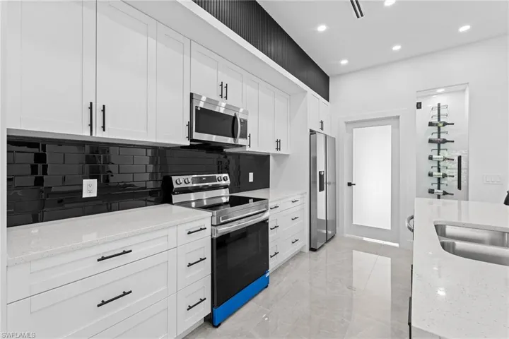Kitchen with stainless steel appliances, white cabinetry, and sink