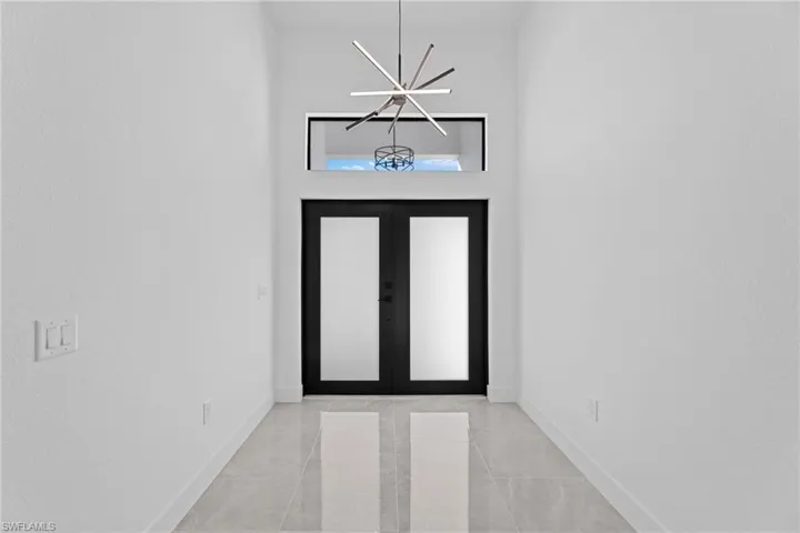 Entrance foyer with french doors and a notable chandelier