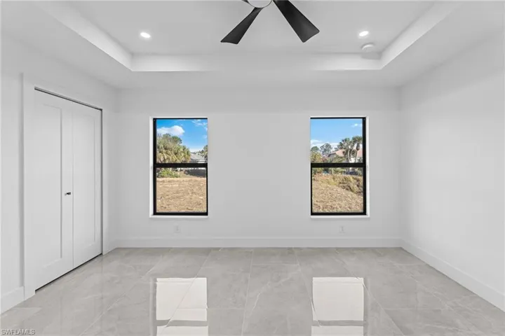 Unfurnished bedroom with ceiling fan, a tray ceiling, and a closet