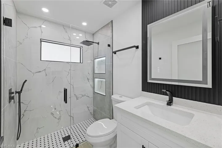 Bathroom with vanity, a shower with door, and toilet