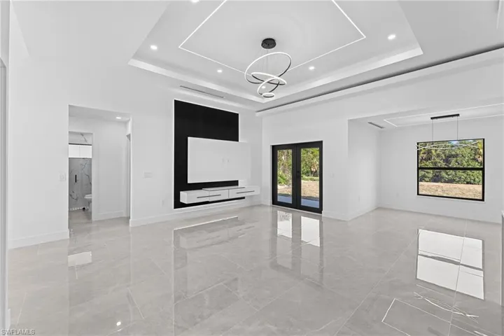 Empty room featuring french doors, a towering ceiling, a notable chandelier, and a tray ceiling