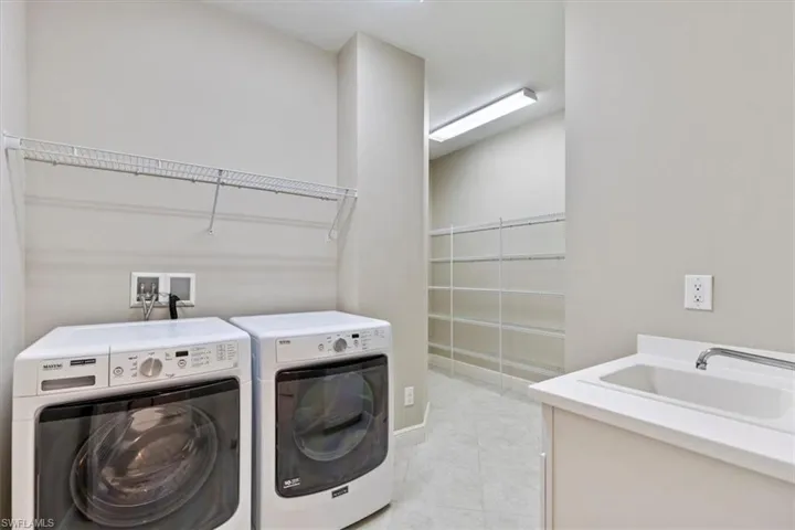 Laundry room featuring sink, light tile patterned floors, and washing machine and dryer